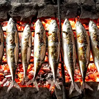 Peixes inteiros a grelhar sobre brasas