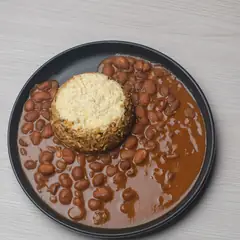 Feijão guisado à volta de uma porção de arroz