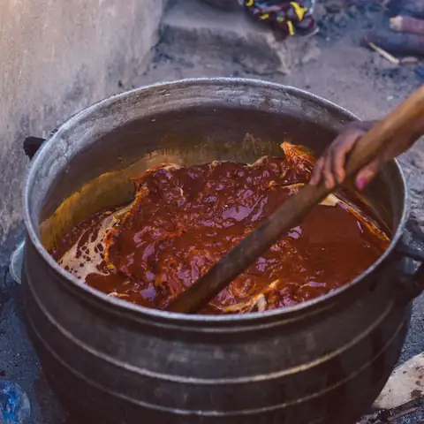 Panela de ferro ao lume com molho vermelho e colher de pau